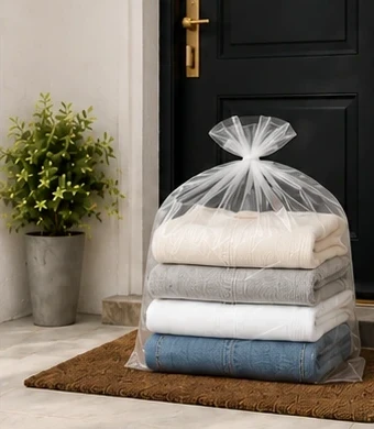 Folded laundry returned in a clear bag on the doormat at the customer's door.